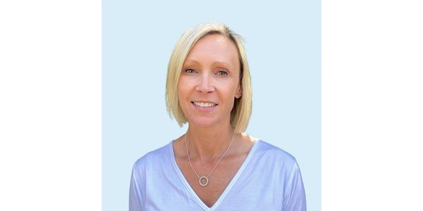 Smiling woman with short blonde hair in a light blue top.