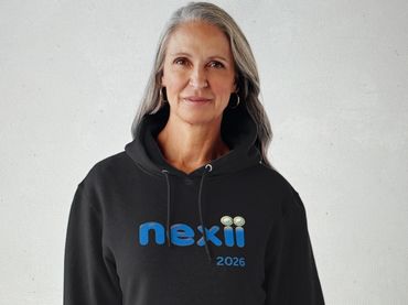 Woman wearing a black hoodie with 'nexii 2026' printed on it.