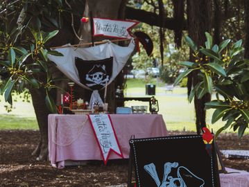Outdoor pirate-themed party setup with skull flags and decorations.