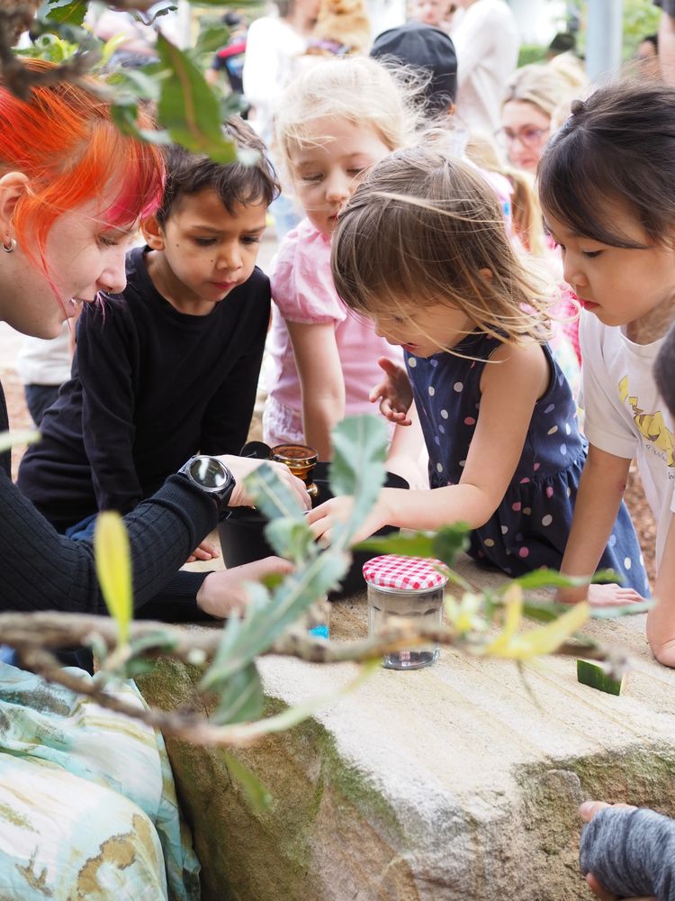 Children gathered around an adult during an outdoor activity.