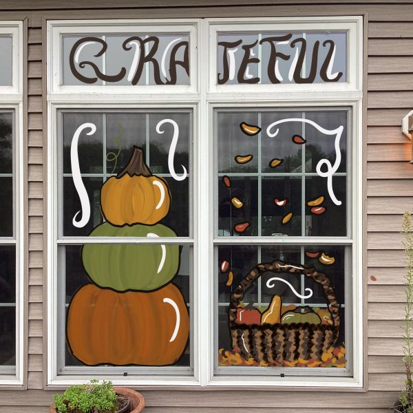 Fall-themed window painting with pumpkins and basket.