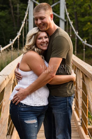 Couple hugging happily on a wooden bridge.