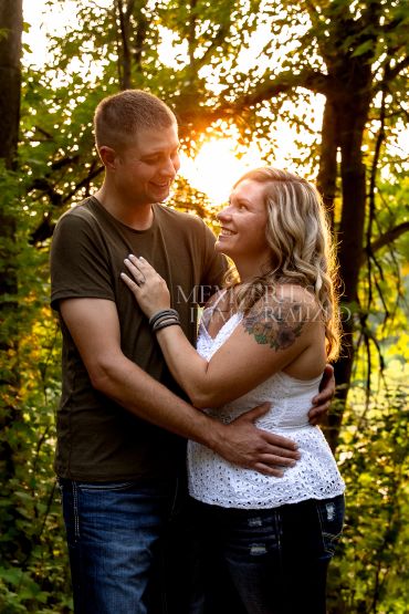 Couple embracing in a sunlit forest.