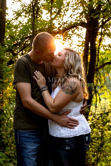 Couple kissing in the forest at sunset.