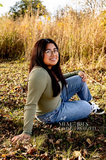 Young woman sitting on grass in autumn.