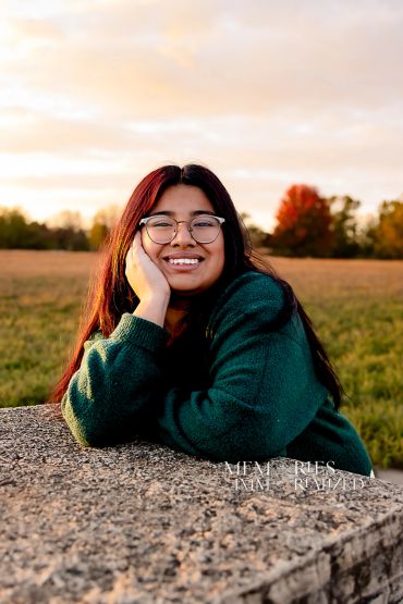 Smiling woman in glasses relaxing outdoors during sunset.