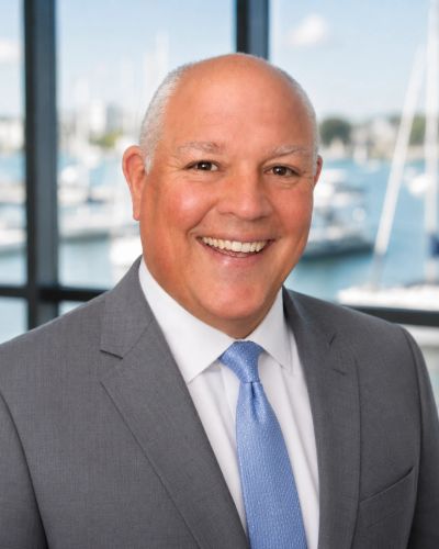 Smiling bald man in suit with a marina background.