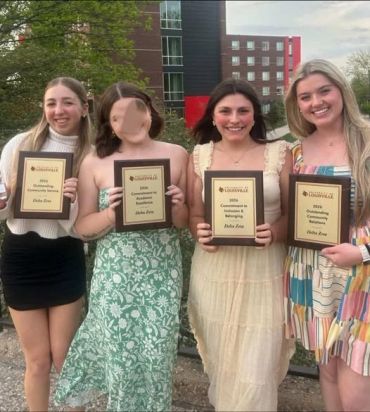 Four young women holding plaques and smiling.