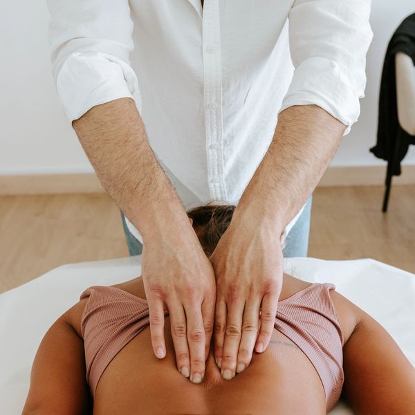 Therapist giving a back massage to a client lying face down.