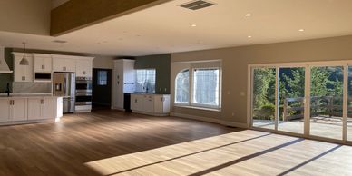 Spacious modern kitchen and living area with large windows and wooden floors.