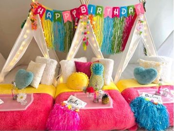  brightly decorated indoor sleepover party setup with three teepees, colorful blankets and pillows, 