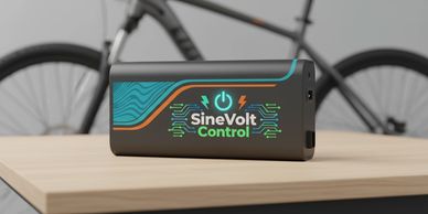 SineVolt Control electronic device on a wooden table with a bicycle in the background.