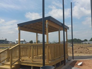 New wooden gazebo structure with a ramp under a partly cloudy sky.