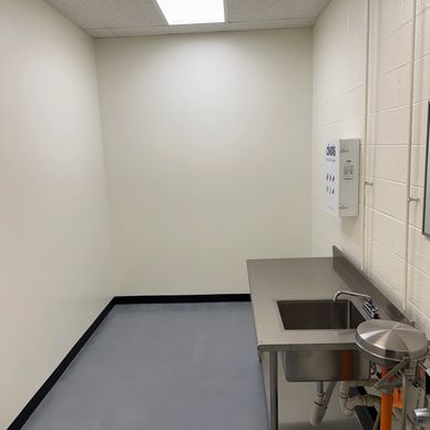 A clean utility room with a stainless steel sink and beige walls.