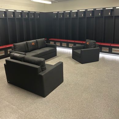 Locker room with black couches and red benches surrounding black lockers.