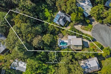 Aerial view of a house with a pool in a wooded area.