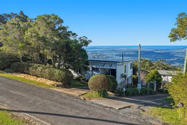 House on a hillside with ocean view and clear blue sky.