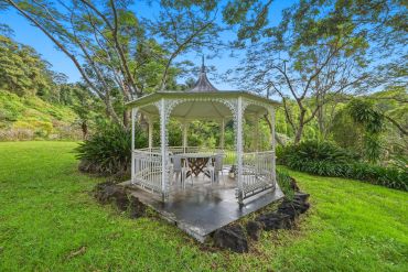 White gazebo in a lush green garden.