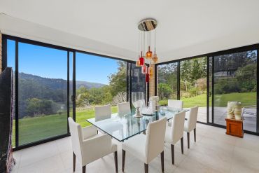 Modern dining room with glass table and scenic view.