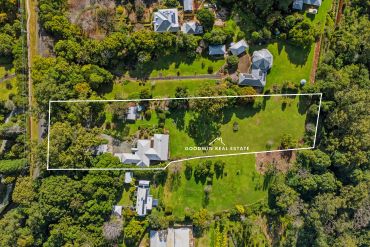 Aerial view of a large property outlined in white within a green landscape.