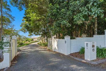 Driveway leading to a house surrounded by trees.
