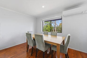 Modern dining room with wooden table and six chairs.
