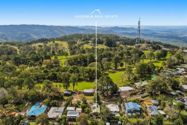 Aerial view of a rural residential area with greenery and hills.