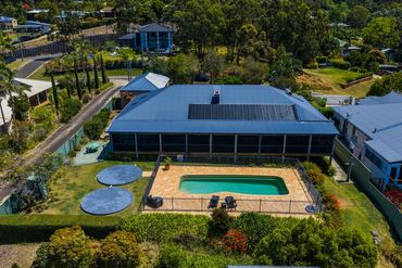 Aerial view of a house with a swimming pool and solar panels on the roof.