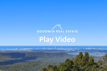 Scenic view of a city skyline from a forested hill under a clear blue sky.