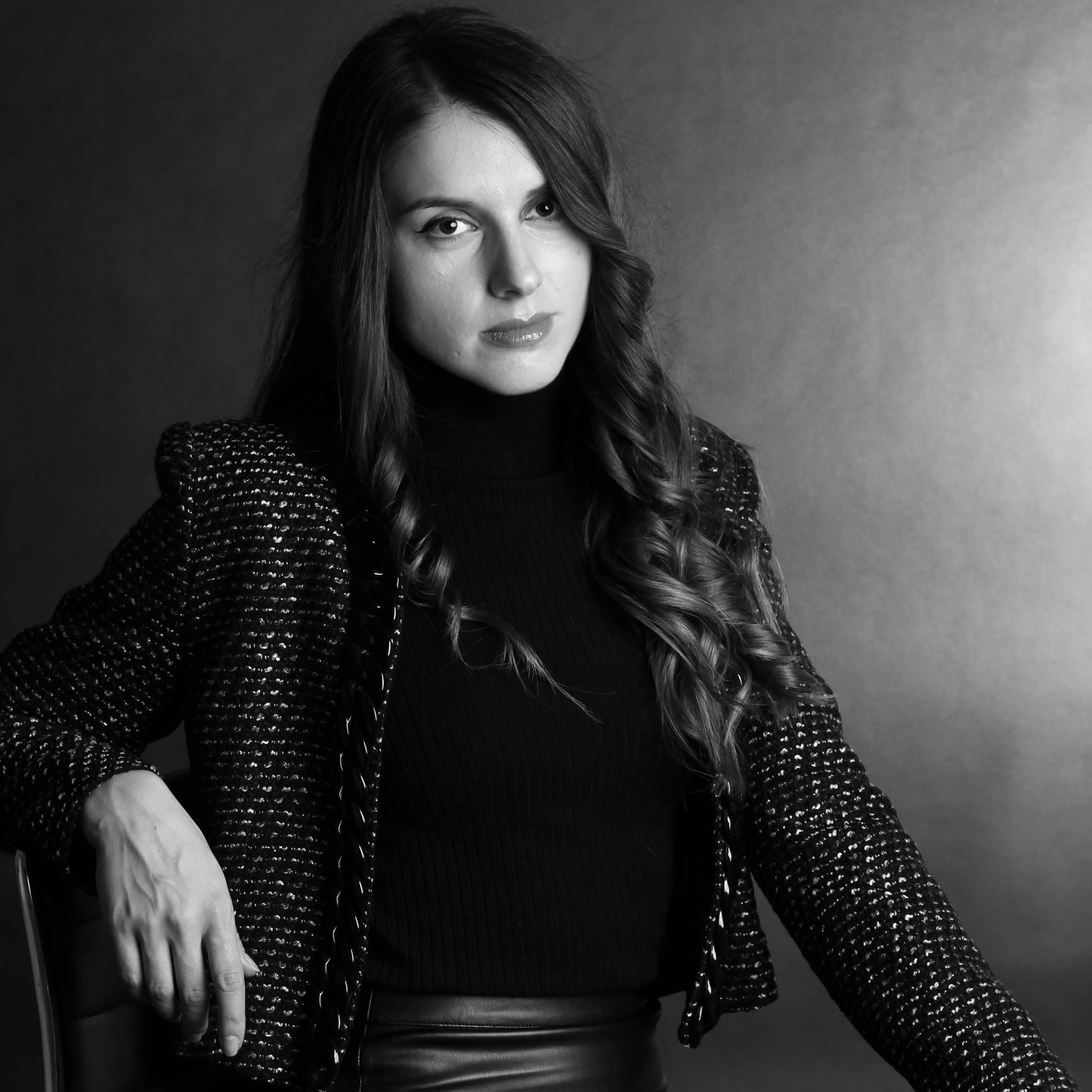 Black and white portrait of a confident woman with long hair and stylish attire.