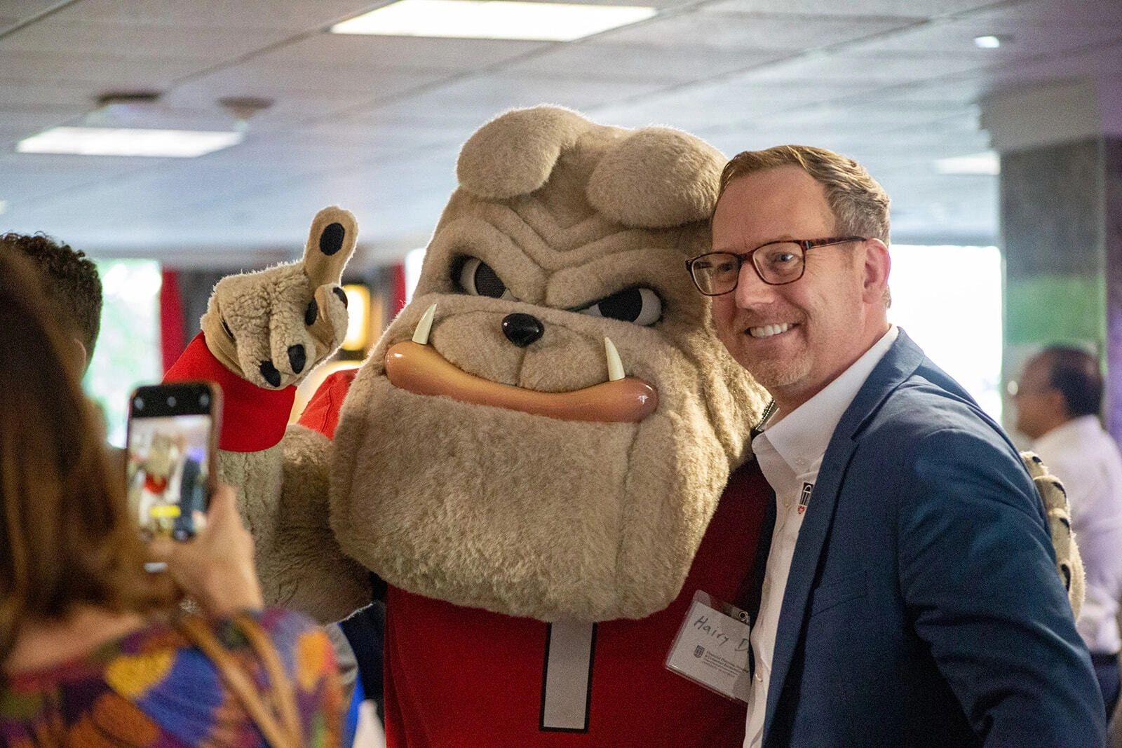 Man posing with bulldog mascot for photo.