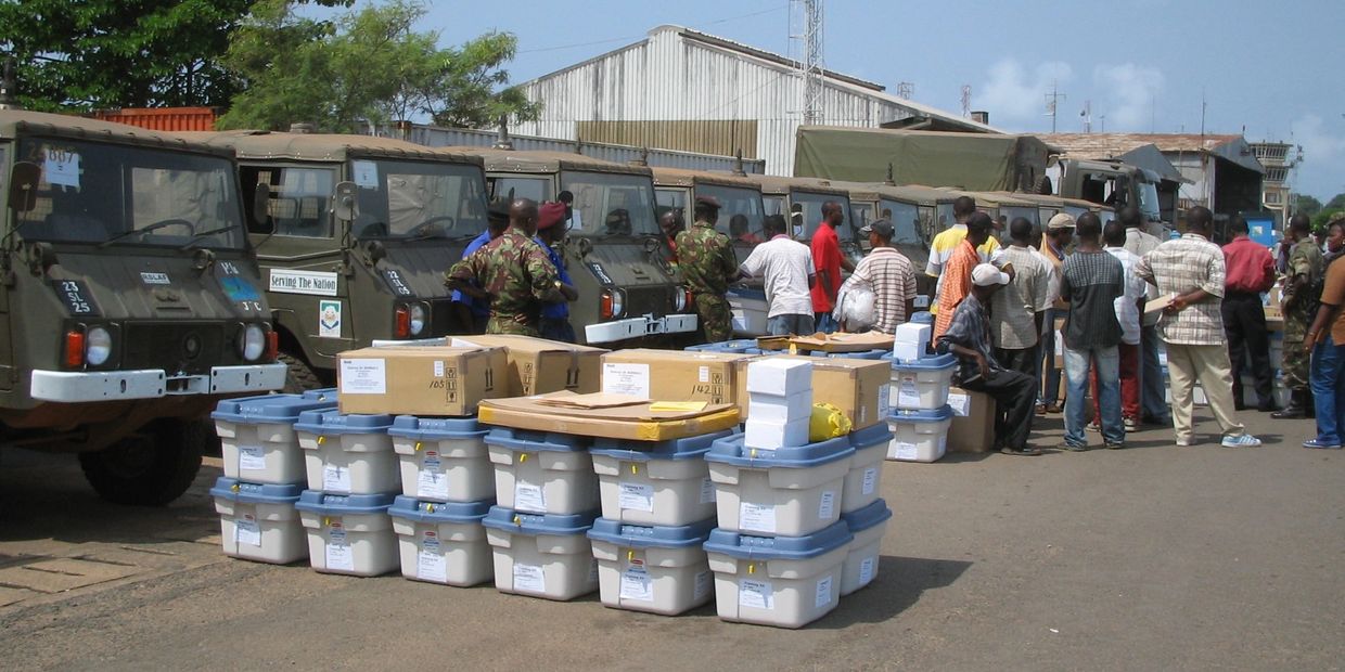Military personnel and civilians with supplies and vehicles.