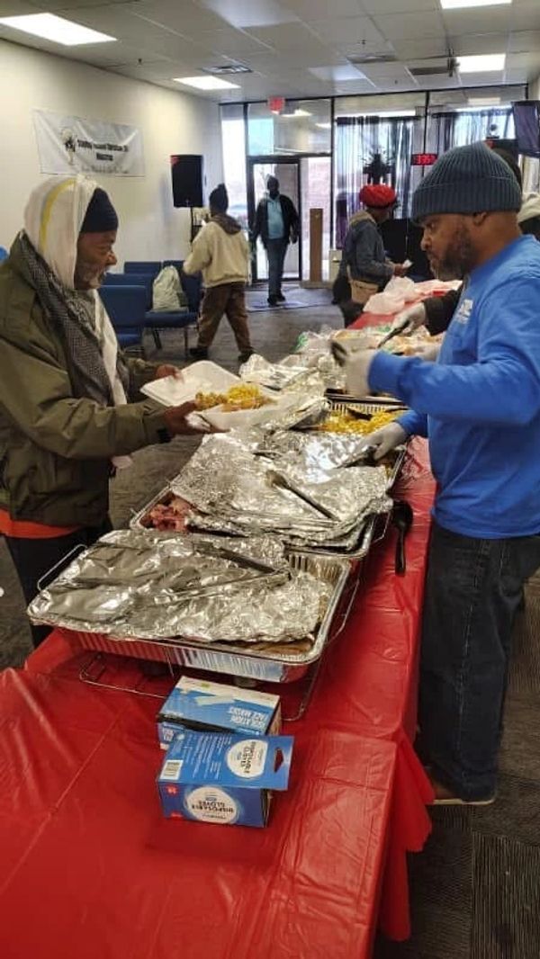 Volunteers serving food to people in a community center.