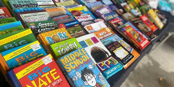 Table filled with colorful children's books arranged for sale or display.