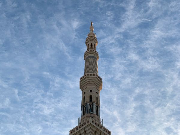 The image captures the minaret of the Prophet’s Mosque standing tall beneath a morning sky adorned with early dawn clouds, creating an atmosphere of tranquility and spirituality. The intricate details of the minaret’s structure are highlighted, harmonizing with the expansive sky, showcasing the architectural beauty that defines this sacred Islamic landmark.