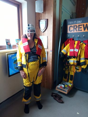 Person wearing a bright safety suit and goggles indoors.