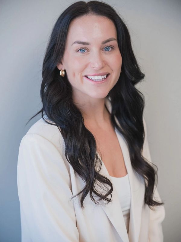 Smiling woman with long black hair in a white blazer.
