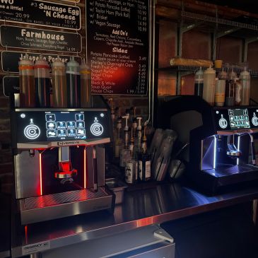Modern coffee machines with syrup bottles on a counter.
