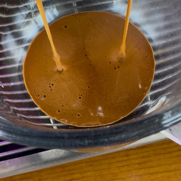 Fresh espresso flowing into a glass container.