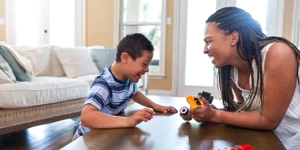 A child with cerebral palsy plays with his female therapist during ABA therapy.