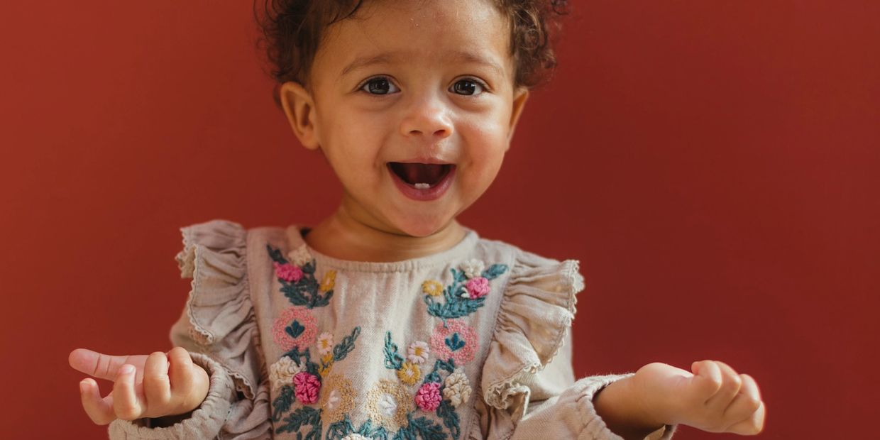 A young girl with two teeth makes hand motions in early intervention therapy.