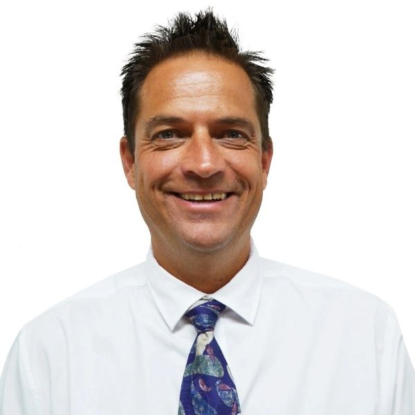 Smiling man in a white shirt and colorful tie against a white background.