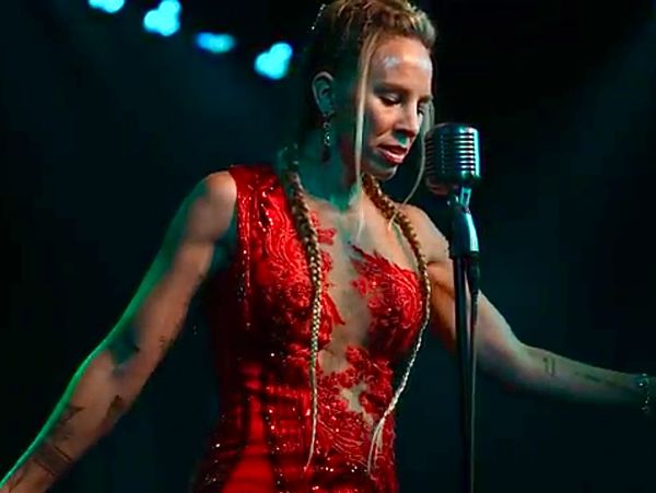 Woman singing in a red dress on stage.