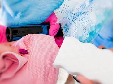 A person wearing pink gloves cleaning a surface with a sponge and cloth.