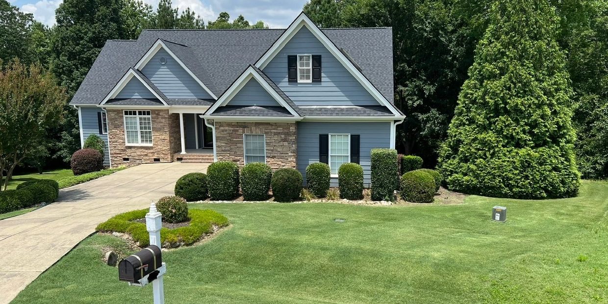 A charming blue house with a well-manicured lawn and driveway.
