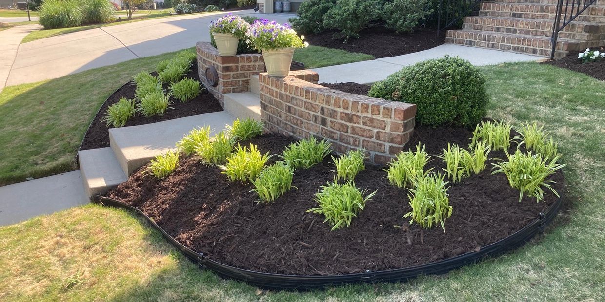 Well-maintained garden bed with fresh mulch and green plants near brick steps.