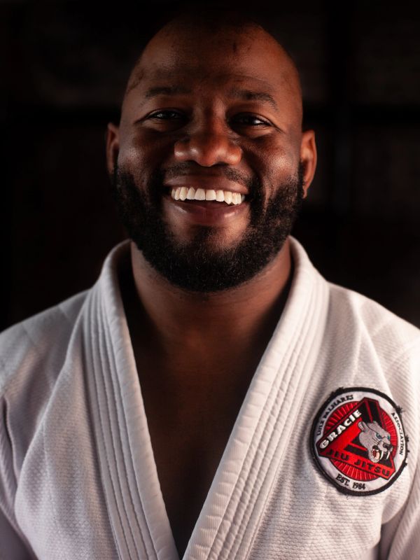 Smiling man in a white Gracie Jiu Jitsu gi with a beard.