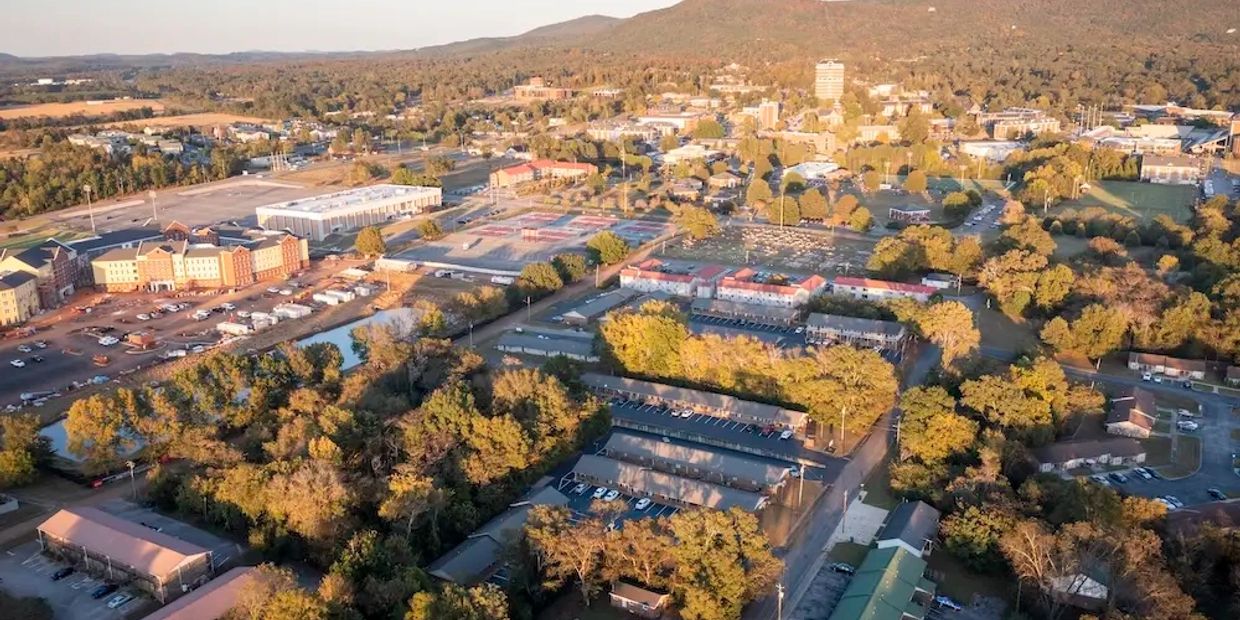 Aerial view of a suburban area with buildings, trees, and hills in the background.