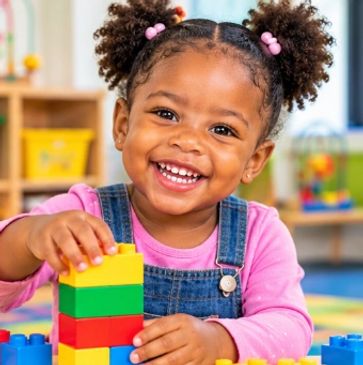 Smiling little girl playing with colorful building blocks.