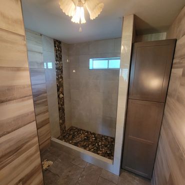 Modern bathroom with pebble stone shower floor and wooden accents.